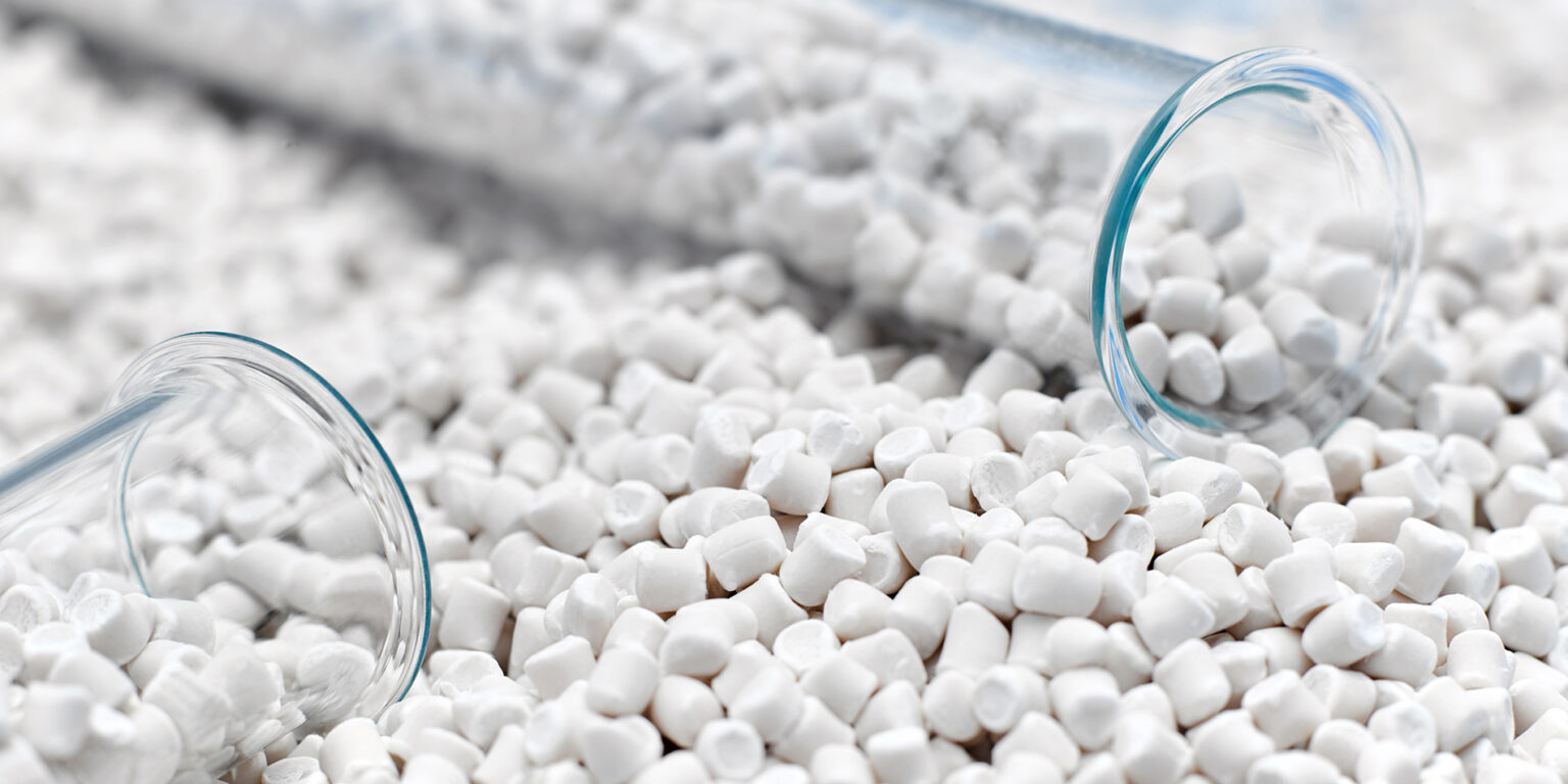 White plastic resin pellets spilled from laboratory glass tubes, illustrating the role of dual specification in ensuring material consistency and supply chain reliability in the modern plastics industry.
